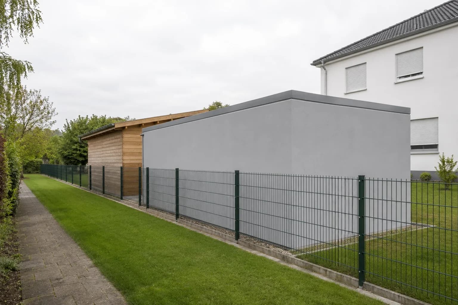 Gartenhaus und Fertiggarage stehen nebeneinander an derselben Grundstücksgrenze